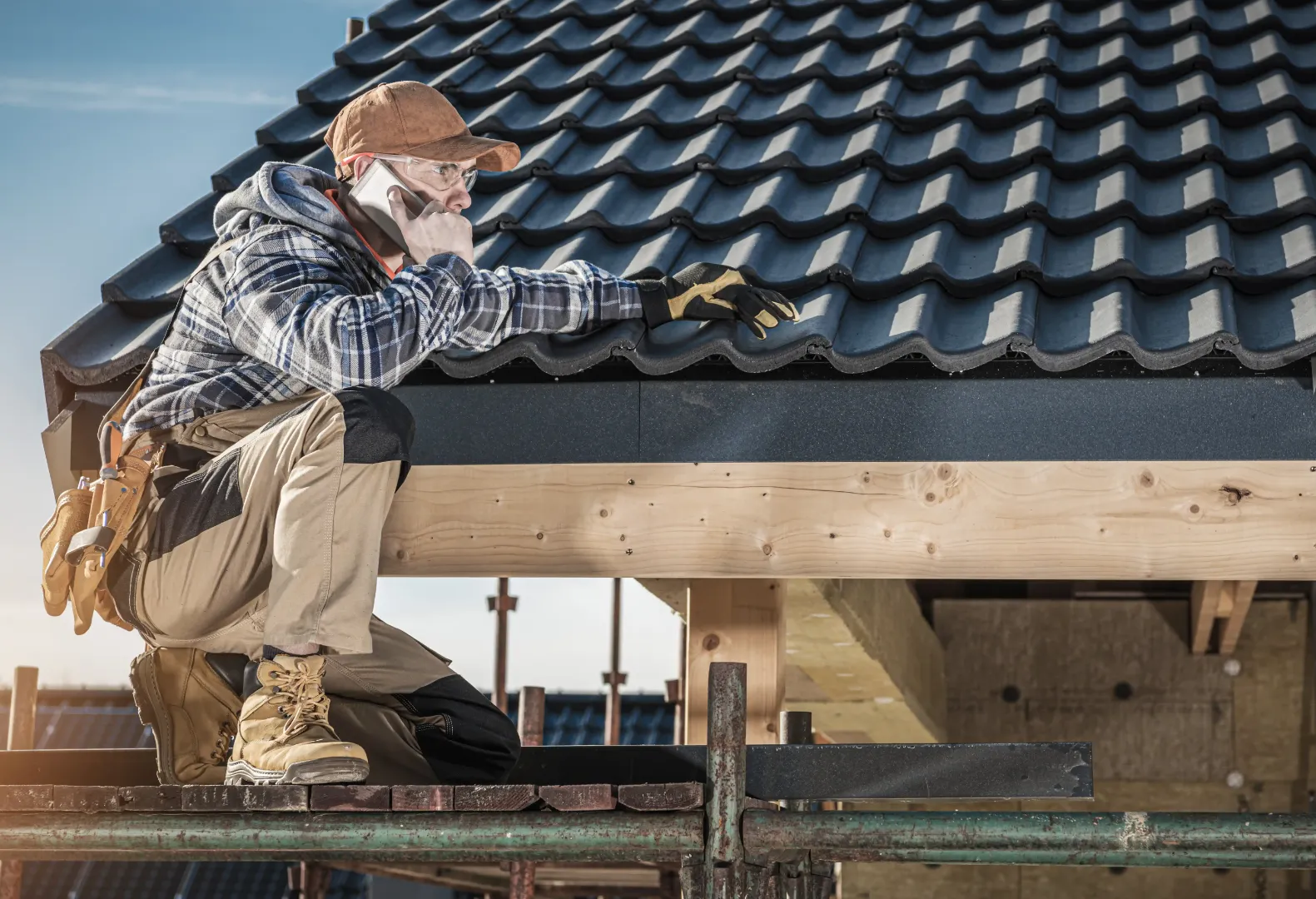 Roofing professional on the phone while reviewing a roof edge